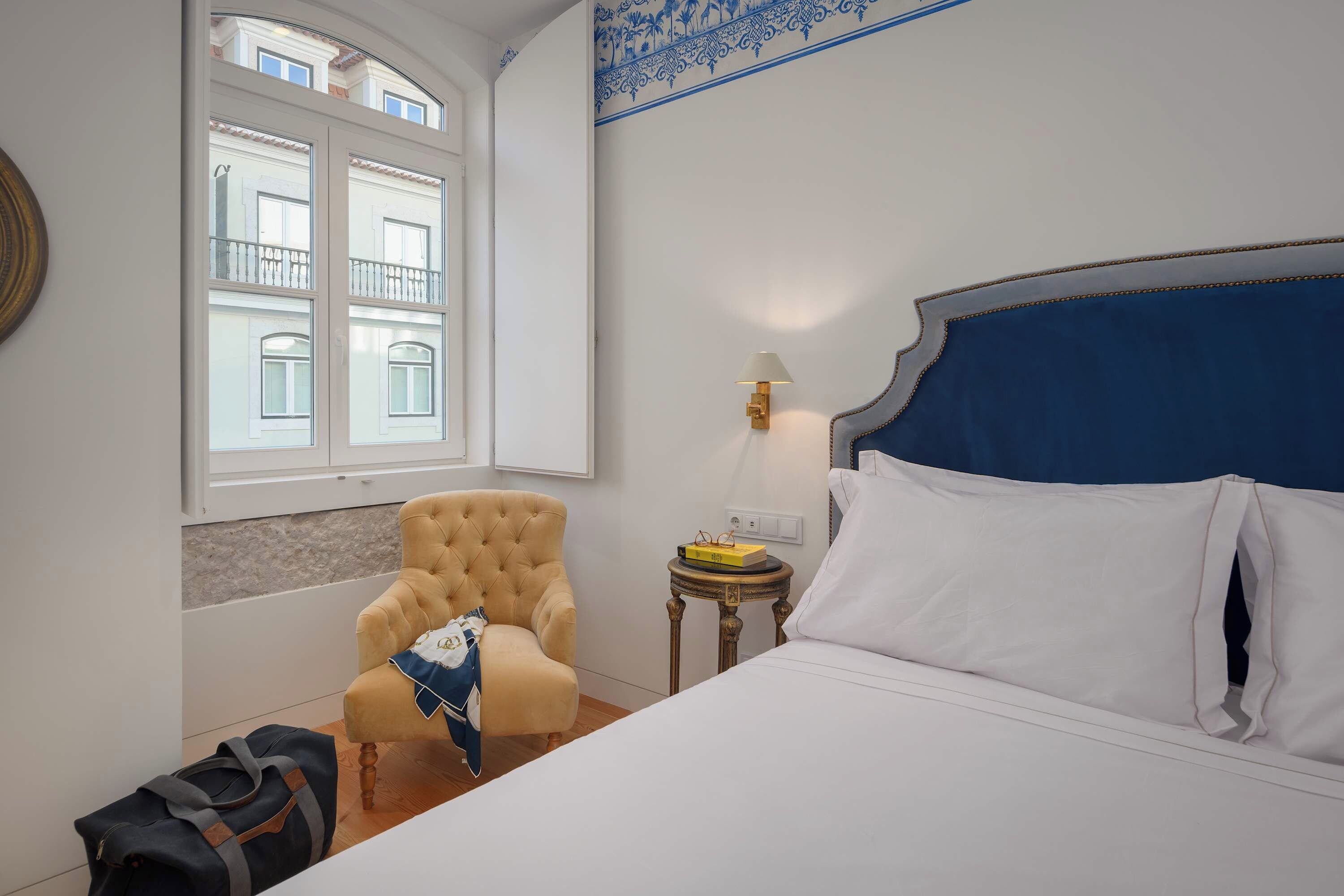 Ein Hotelzimmer mit einem Bett, einem Sessel, einer Lampe und einem Fenster.