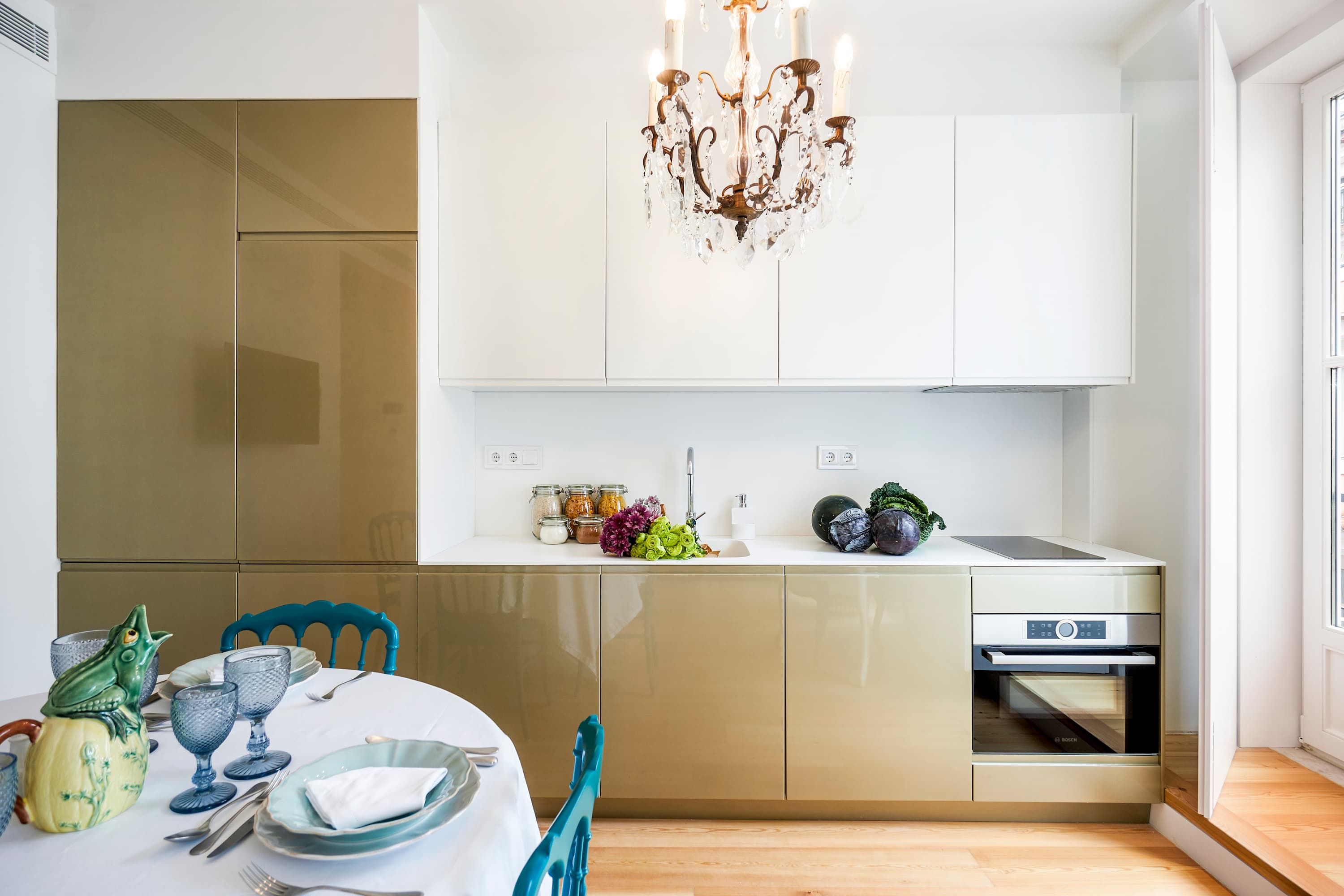 Una cocina moderna con comedor, que incluye un horno Bosch, una araña y una variedad de alimentos sobre la encimera.