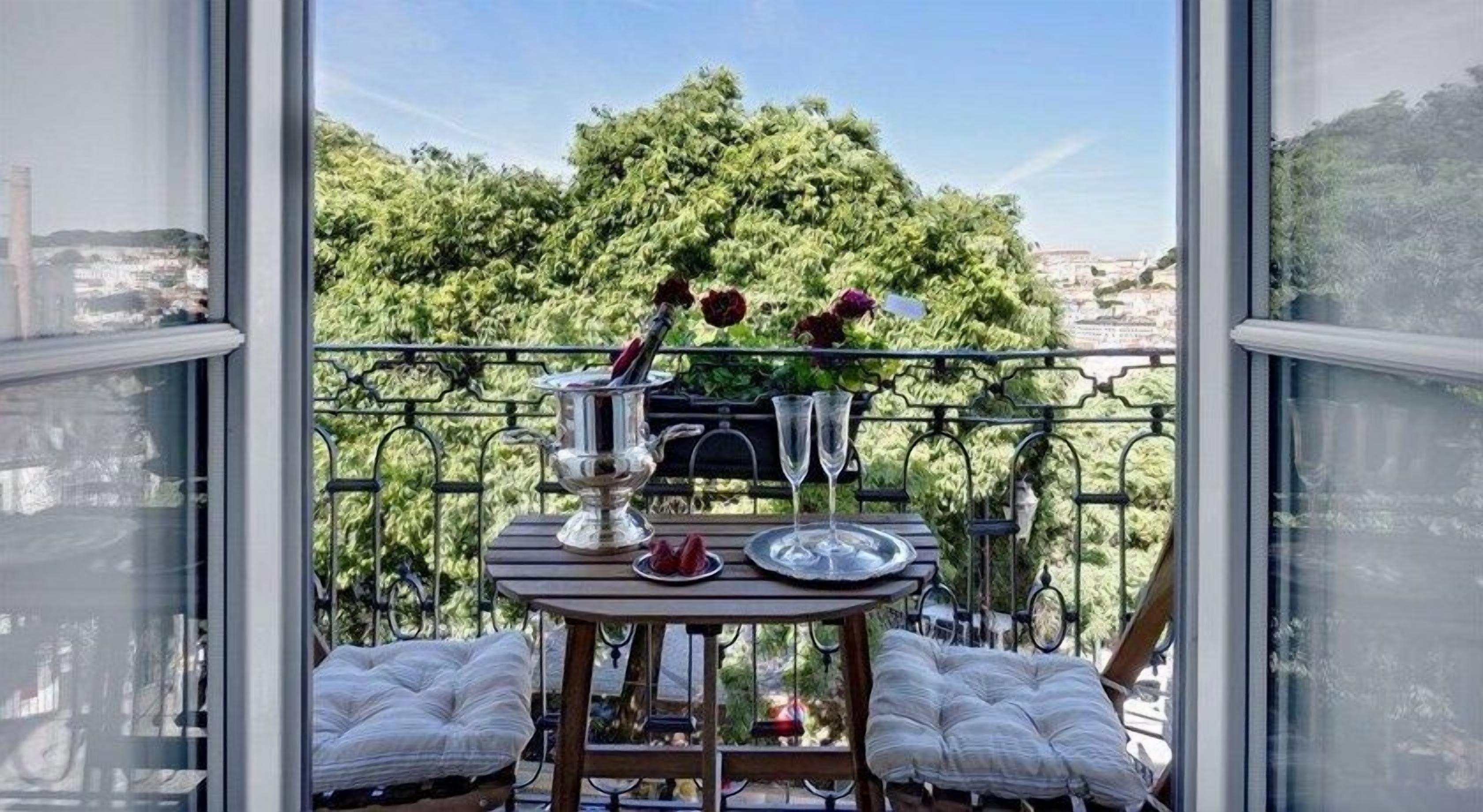 En balkon med et spisebord, en stol og udsigt over et grønt landskab.