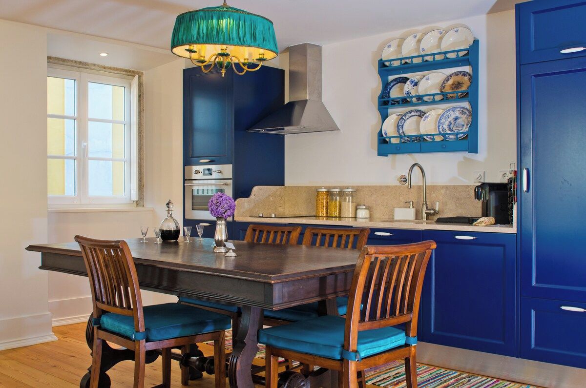 Eine Küche mit einem blauen Schrank, einem Esstisch mit Stühlen und einer Pendelleuchte.