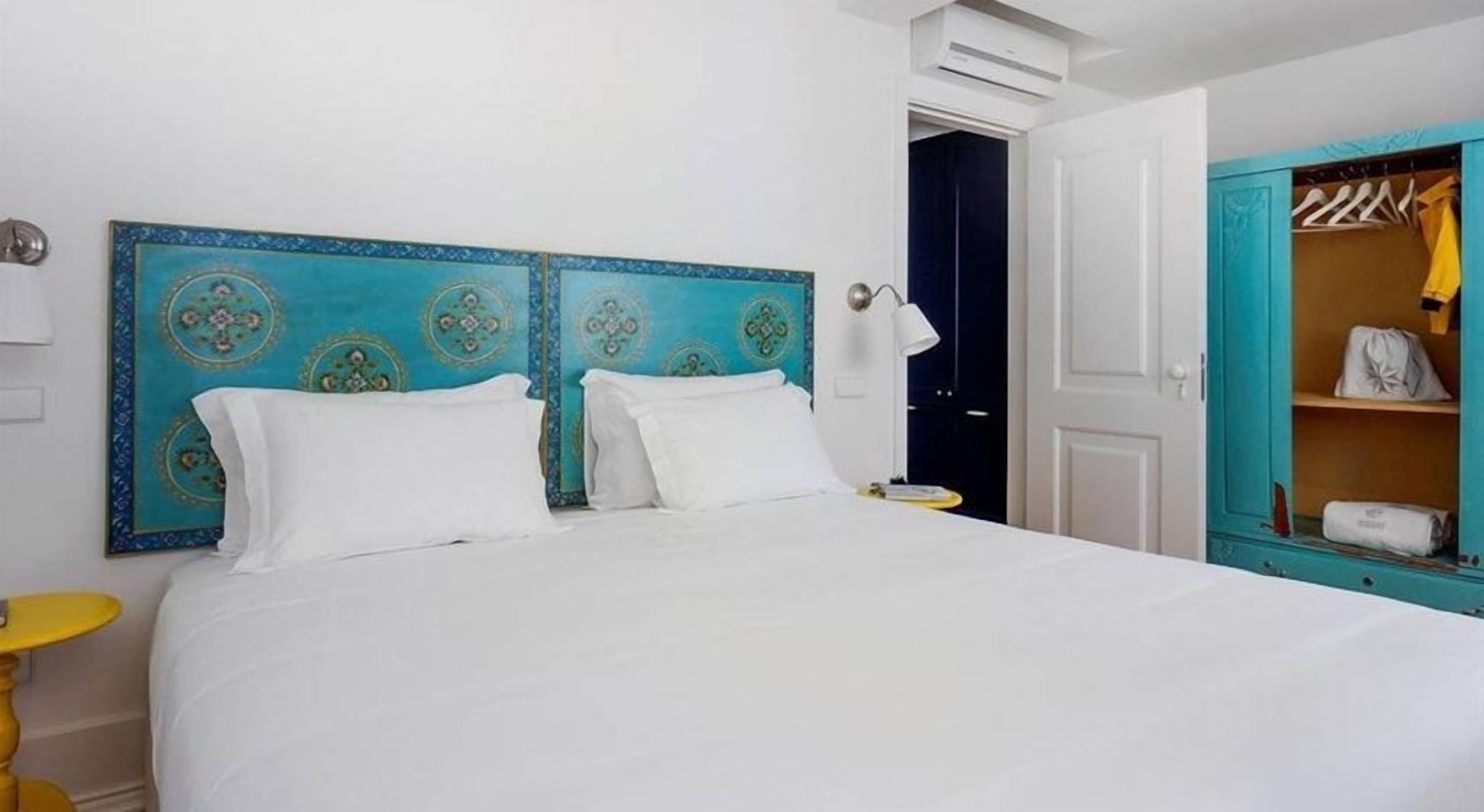 Ein Hotelzimmer mit einem großen Bett, einem Schrank mit Spiegel und einem kleinen Tisch.