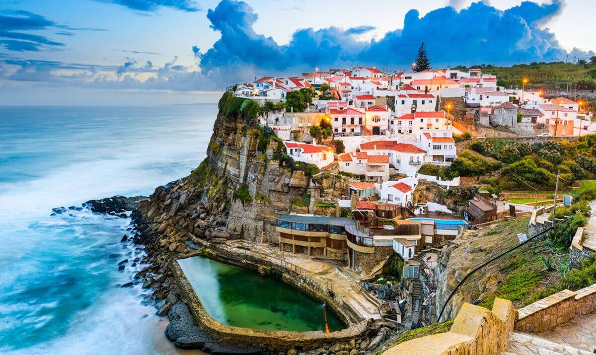 Uma vila costeira com edifícios construídos em um penhasco com vista para o mar.