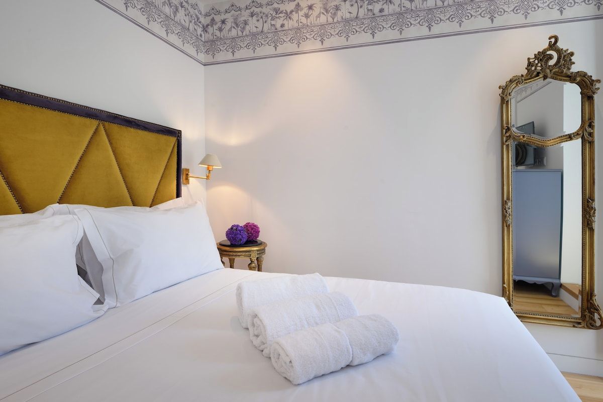 Ein Hotelzimmer mit einem Bett, einem großen Spiegel und einem kleinen Tisch mit einer Lampe.