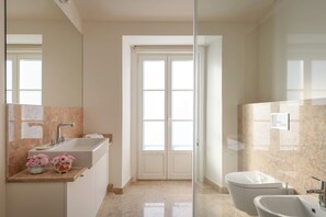 Un baño moderno con un espejo grande, un lavamanos y un inodoro.