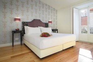 Quarto de hotel com uma cama grande, duas mesas de cabeceira, cabeceira e vista para o exterior.