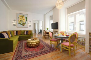 Uma sala de estar espaçosa com um sofá verde, uma mesa de centro redonda e um espaço de jantar com mesa posta para o café da manhã.