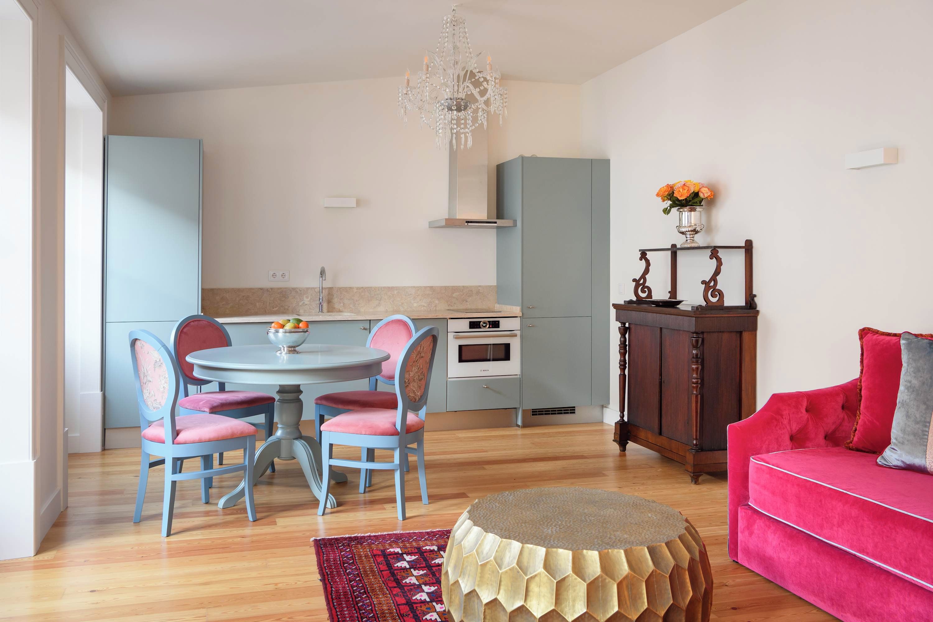 Uma sala de estar moderna com um sofá vermelho, uma mesa de centro redonda e um tapete estampado.