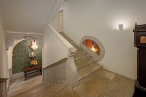 A staircase with stone steps and a wooden handrail, leading to a room with a decorative wall and a bench. - Presidential Suite with Rossio Square Views (Lisbon)