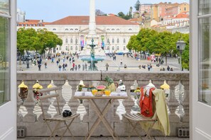A balcony with a table set for breakfast, overlooking a plaza with a fountain and historic buildings. - Presidential Suite with Rossio Square Views (Lisbon)