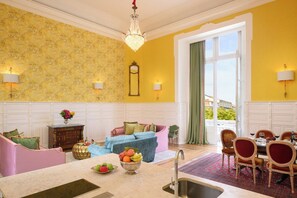 A bright yellow room with a dining area, a sofa, and a chandelier. - Presidential Suite with Rossio Square Views (Lisbon)