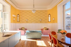 Een moderne keuken met een centraal eiland, een eethoek met tafel en stoelen, en een groot raam dat voor natuurlijk licht zorgt.