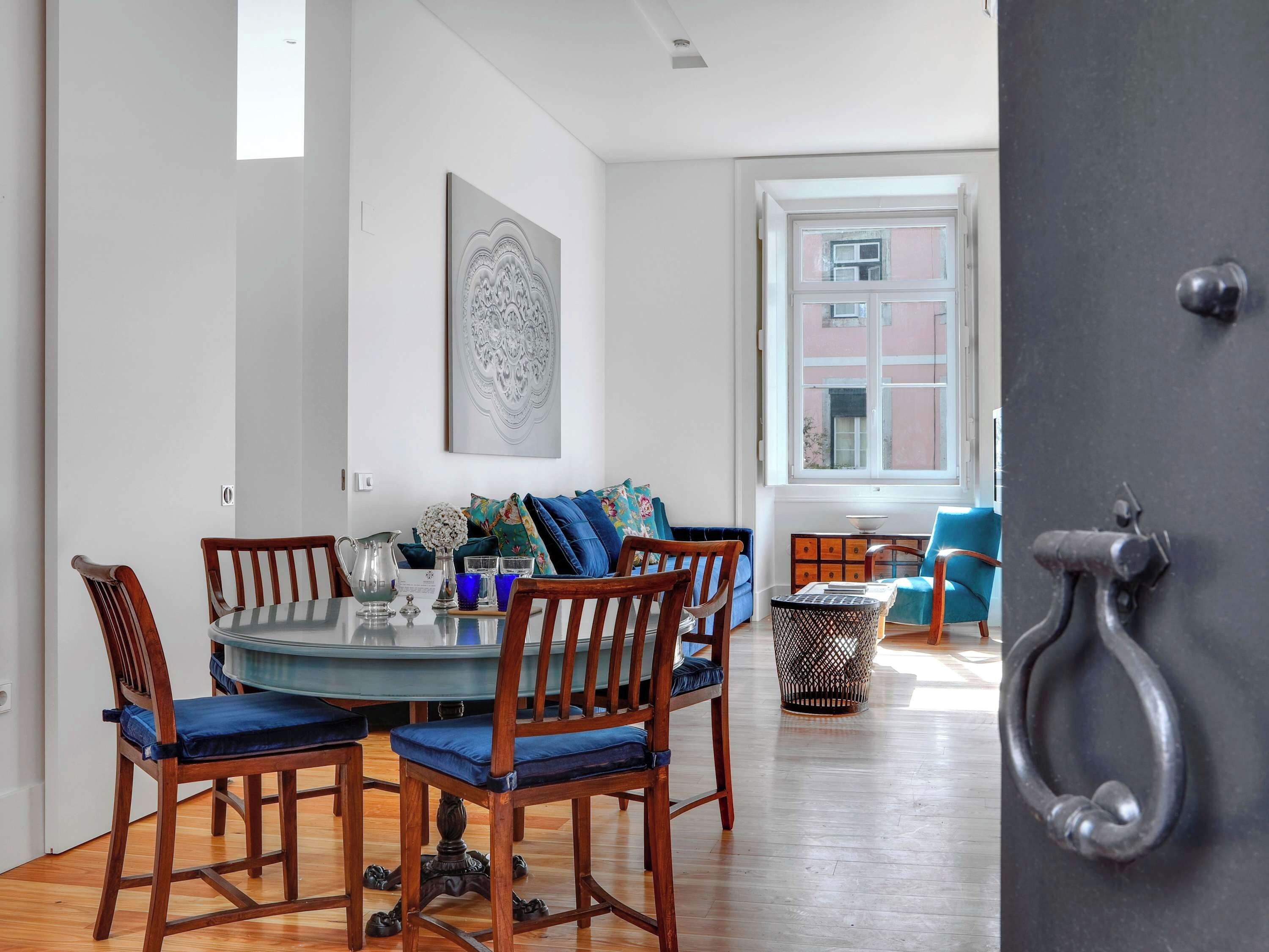 A dining area with a round table, wooden chairs, and a blue cushioned bench.