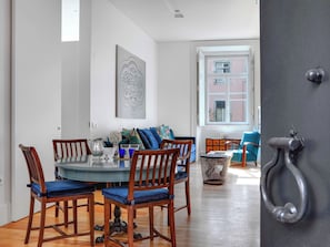 A dining area with a round table, wooden chairs, and a blue cushioned bench. - Historic Lisbon Apartment Near Chiado (Lisbon)