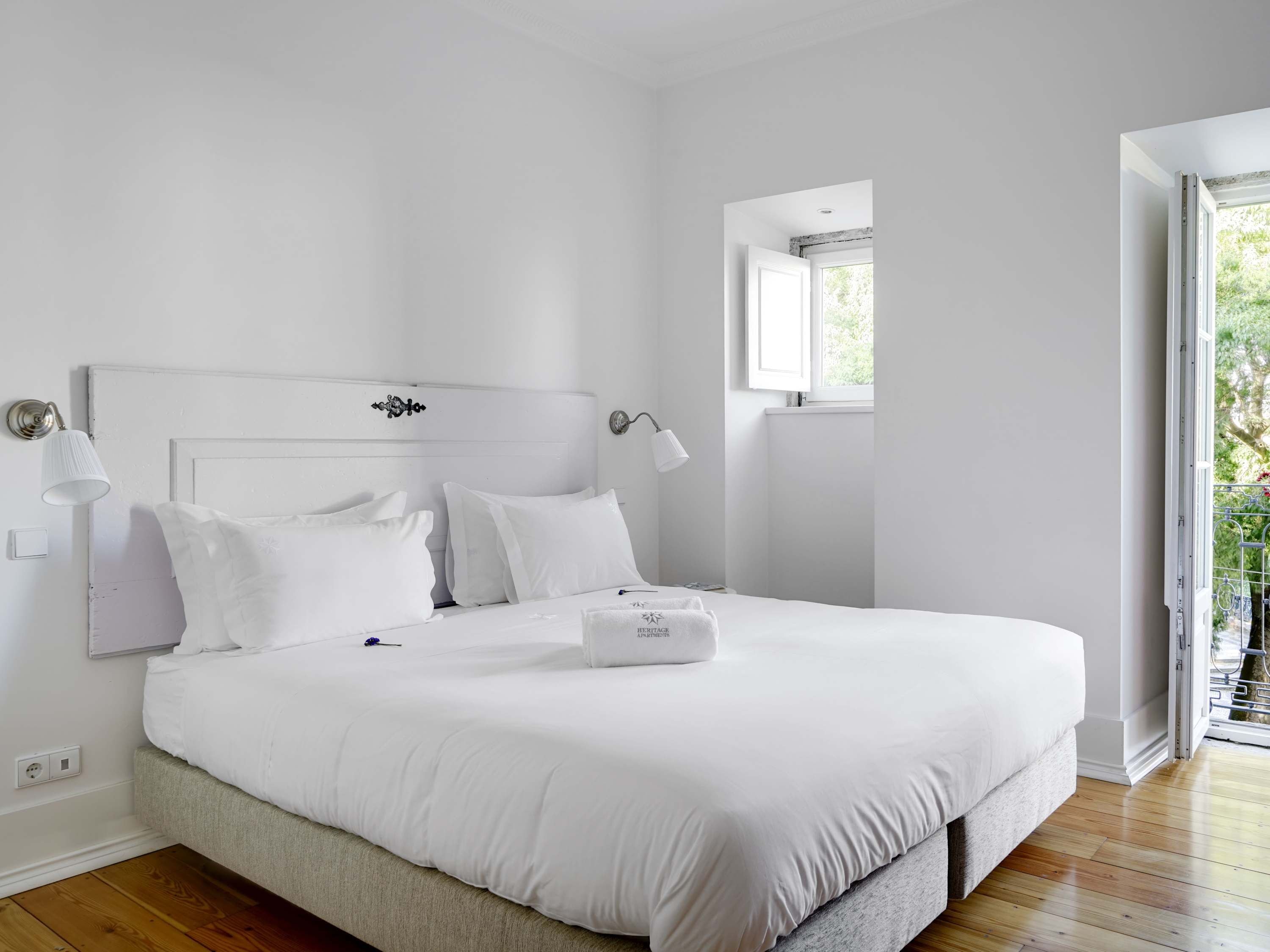 Ein helles Schlafzimmer mit einem Bett, Nachttischlampen und einem Fenster.