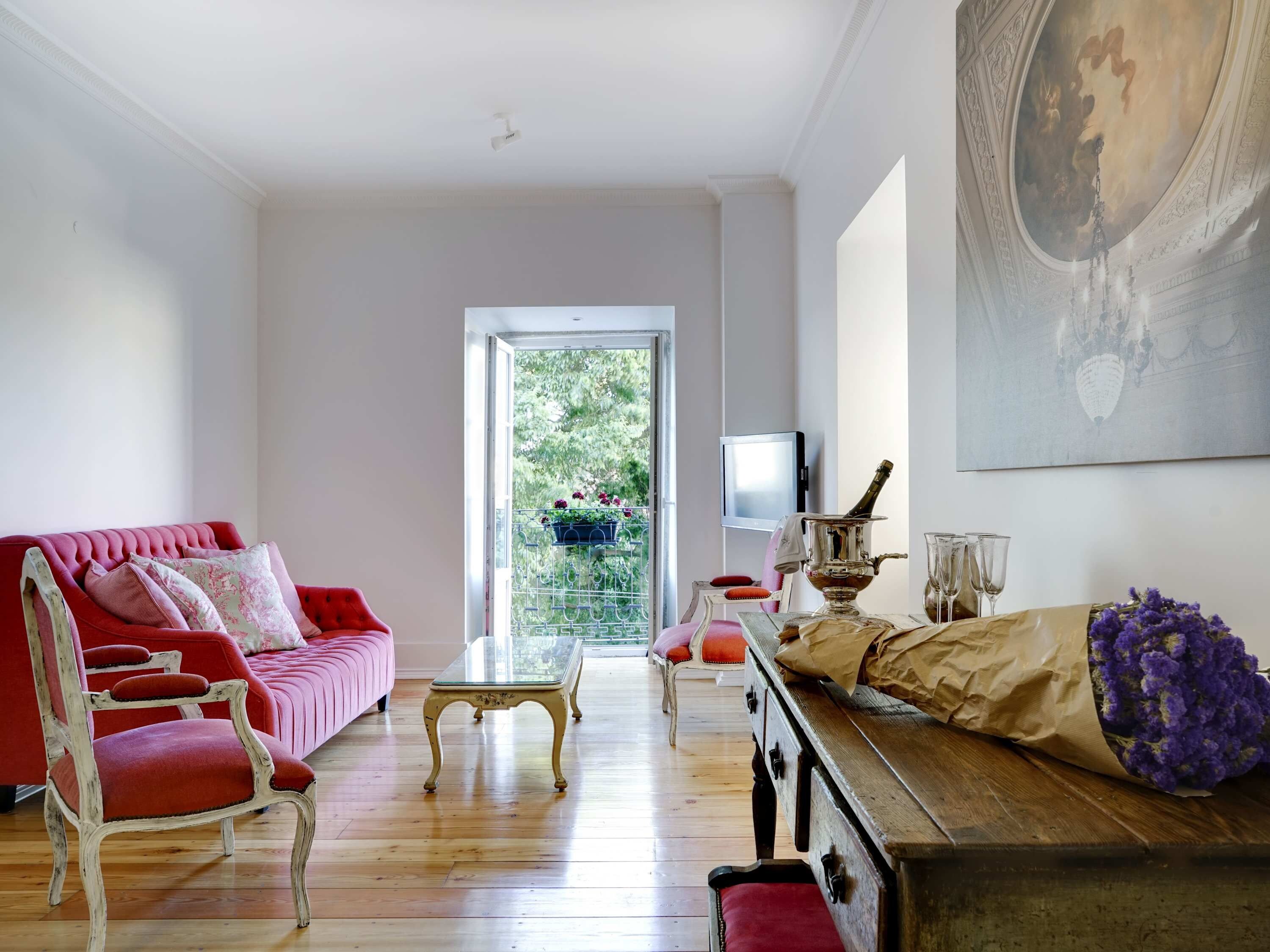 Ein Zimmer mit einer roten Couch, einem Holztisch und einer Vintage-Kommode.