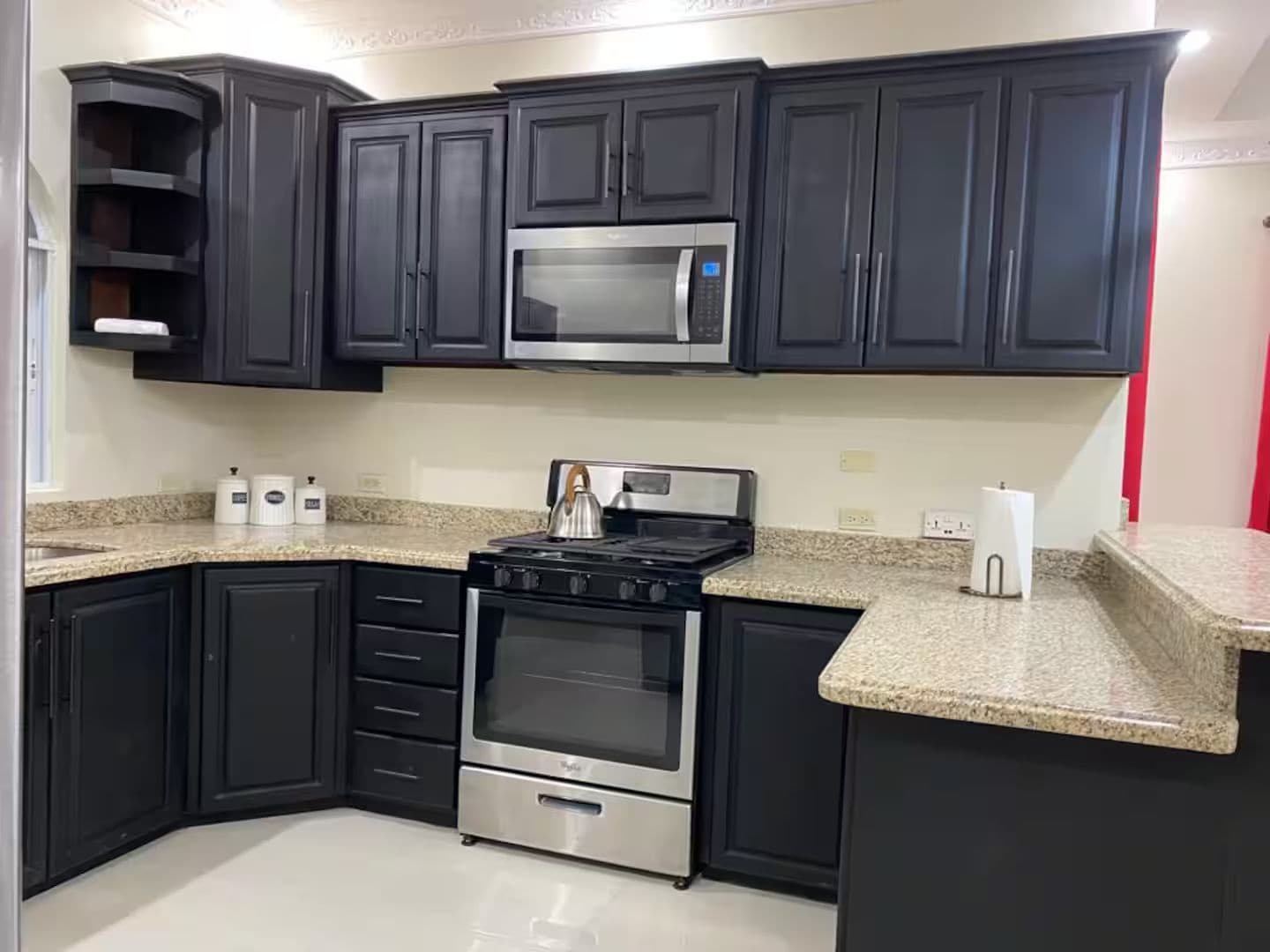 A kitchen with dark cabinets, a stainless steel microwave, a gas stove, and granite countertops.