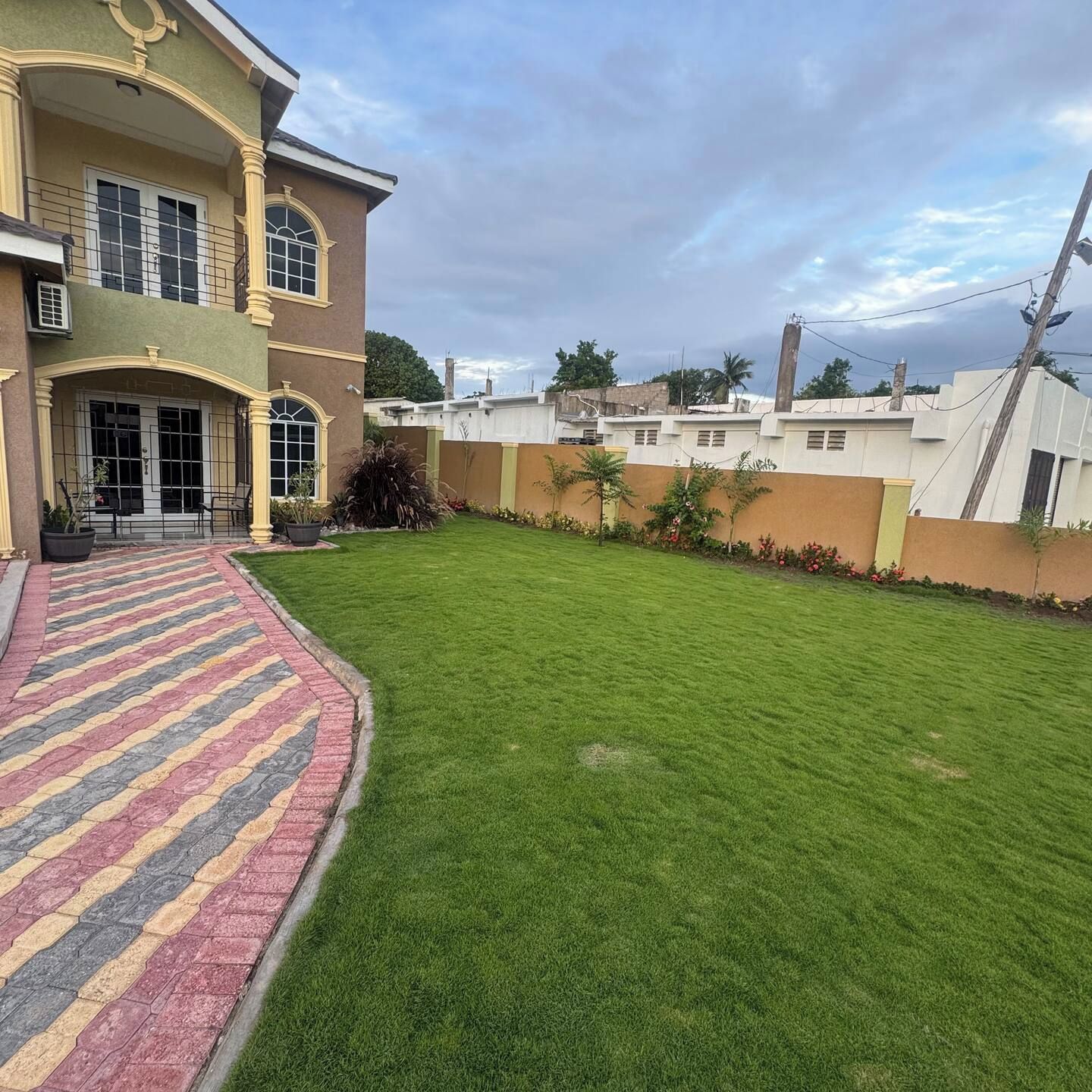 A two-story house with a paved entrance and a well-maintained lawn.