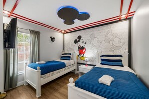 A bedroom with two beds, a Mickey Mouse mural, and a TV on the left. - Emerald Island Corner Townhome  2 King Suites (Kissimmee)