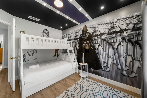 Ein Zimmer mit einem Etagenbett, einer Wandmalerei zum Thema Star Wars und einer Star Wars Actionfigur.