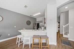 Eine moderne Küche mit einer zentralen Kochinsel, Barhocker und einer Uhr an der Wand.