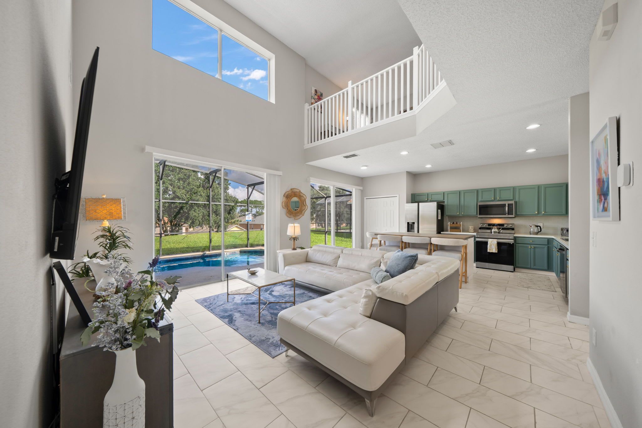 A spacious living area with a large sectional sofa, a dining table, and a kitchen in the background.