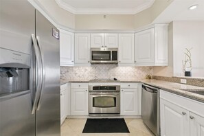 A kitchen with white cabinets, stainless steel appliances, a microwave, oven, and dishwasher.