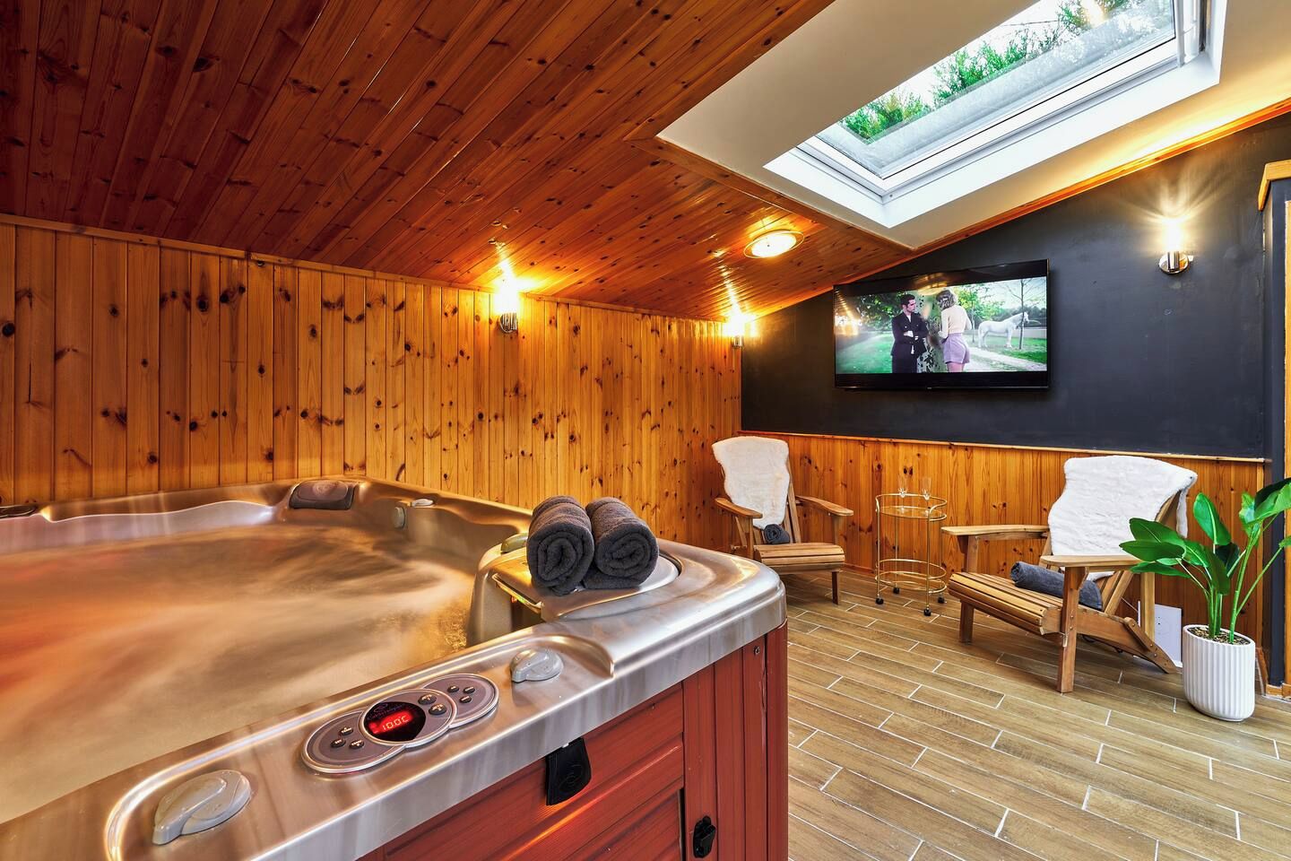 Una sala de sauna con paredes de madera, una bañera de hidromasaje y un televisor montado en la pared.