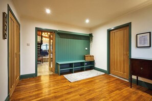 Ein Flur mit Holzboden, einer Bank, einem Korb und einer Tür mit einer Willkommensschild.'