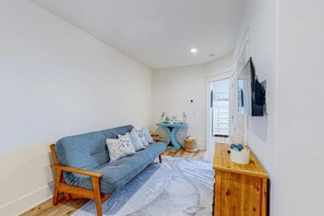 A room with a blue sofa, wooden side table, and a small blue table with decorative items. - The Spotted Sandpiper (Miramar Beach)