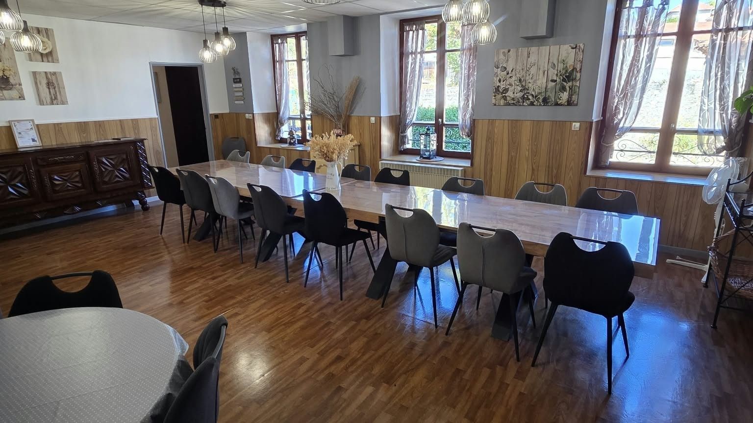 Zona pranzo con un tavolo lungo, diverse sedie e un pavimento in legno.