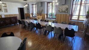 Zona pranzo con un tavolo lungo, diverse sedie e un pavimento in legno.