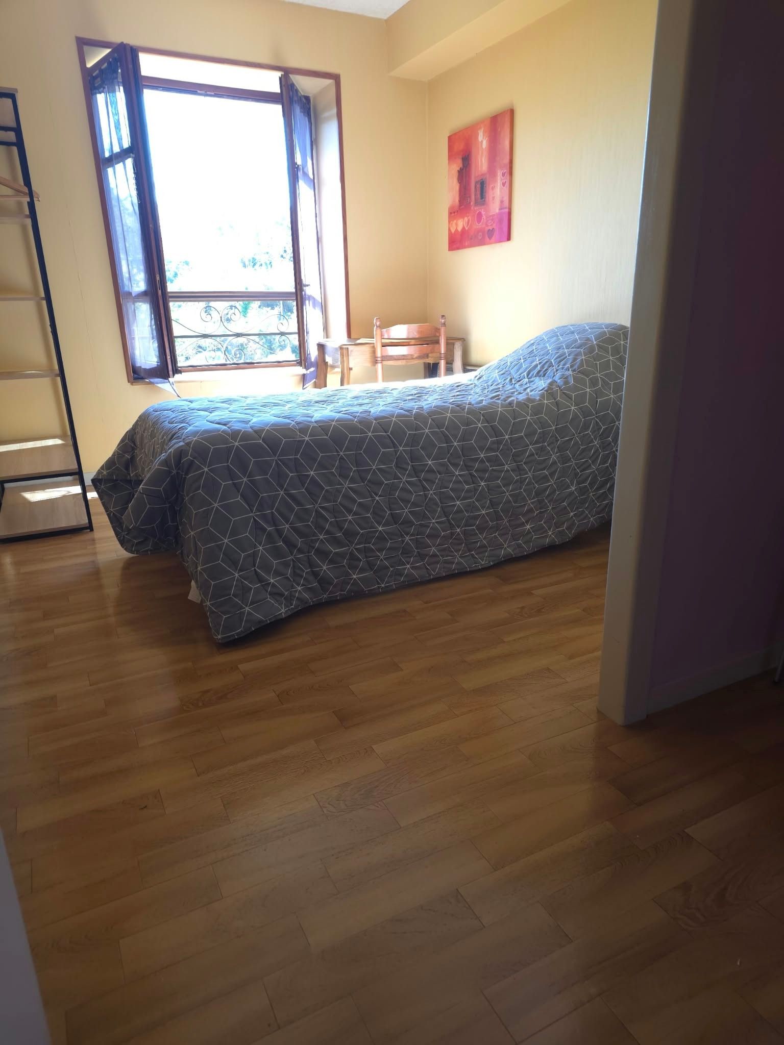 Ett rum med en säng, ett fönster, en stol och en stege.