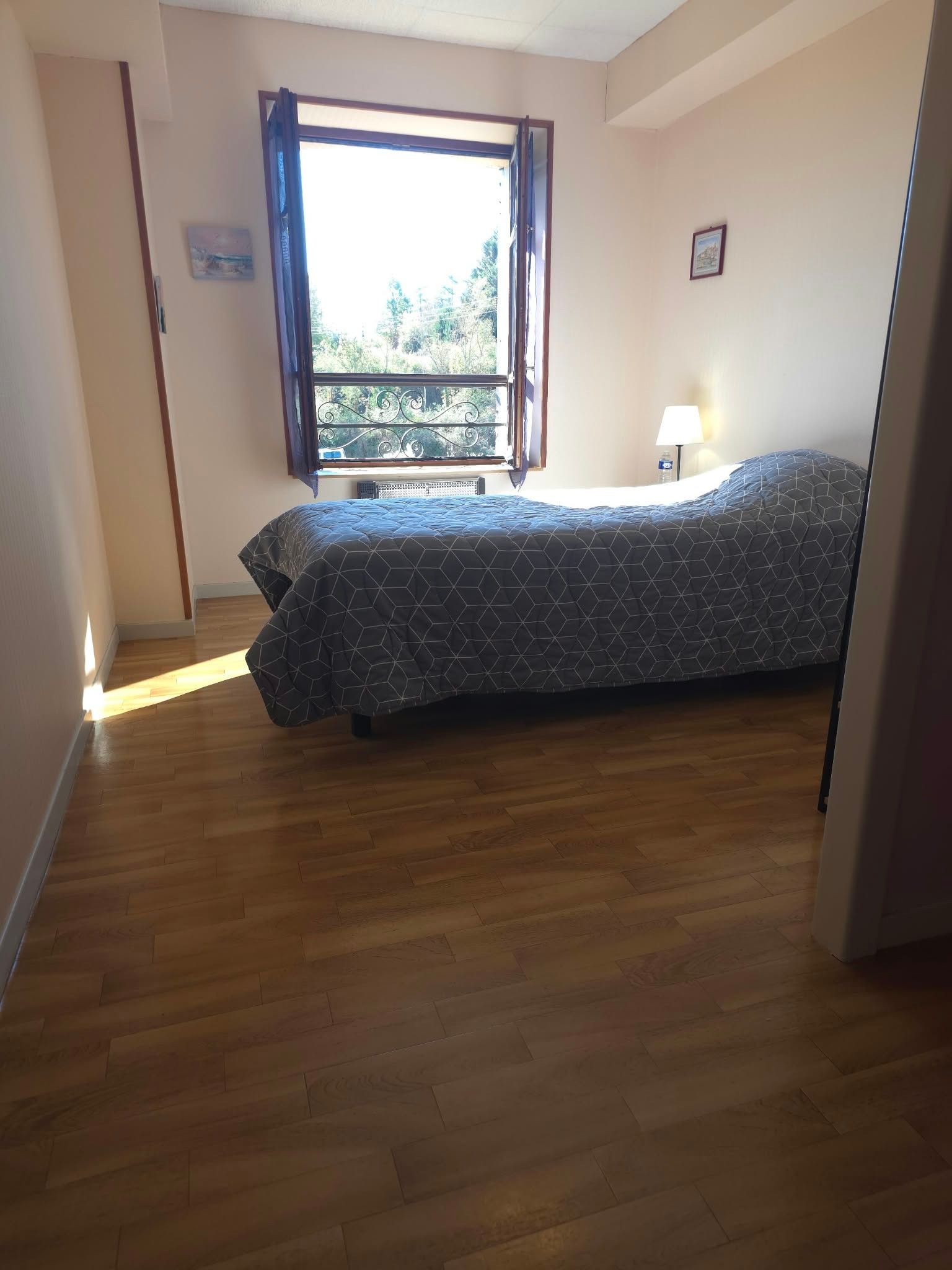 A bedroom with a bed, a window, and a nightstand.