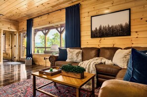 Ein Holzinnenraum mit einer Couch, einem Couchtisch mit einer Pflanze und Blick durch ein Fenster.