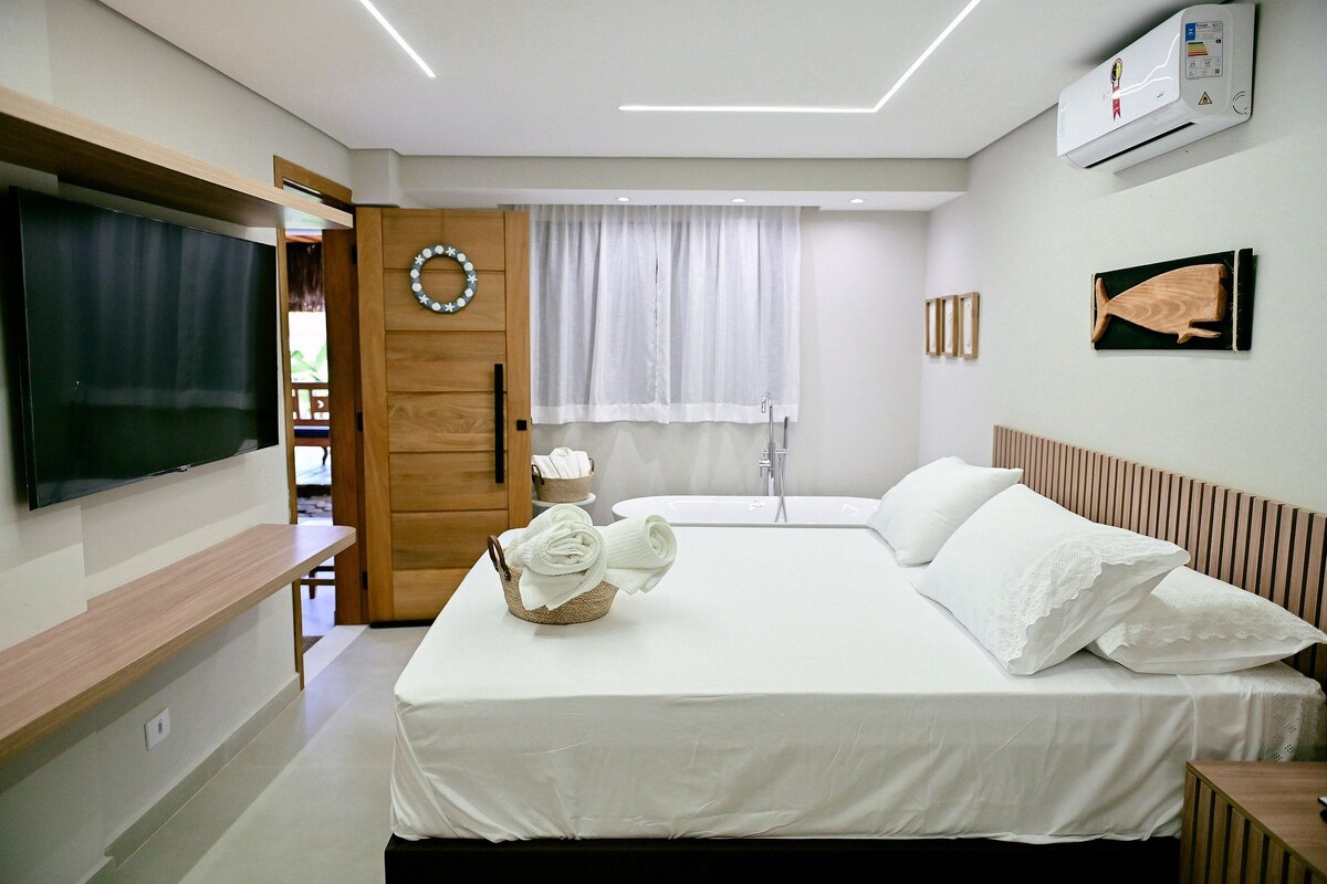 Una habitación de hotel con cama, televisor, ducha y aire acondicionado instalado en la pared.
