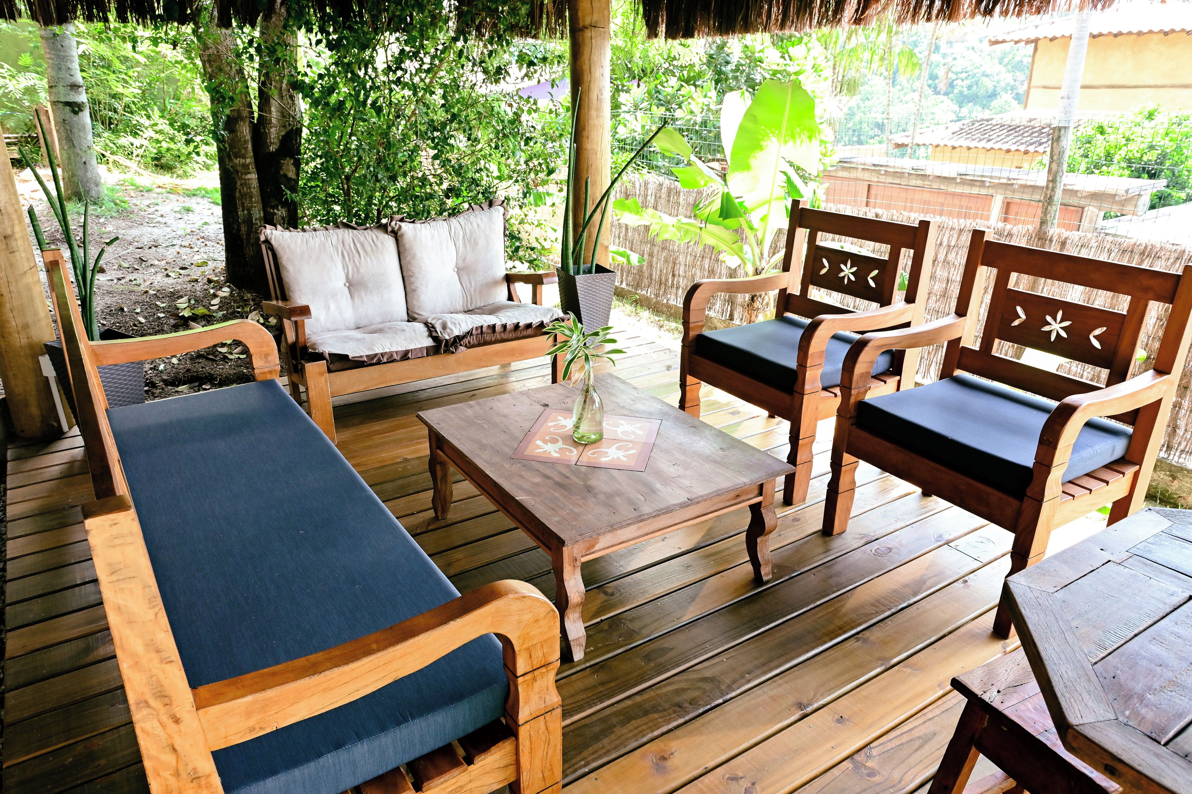Una terraza de madera con un sofá, dos sillones y una mesa.