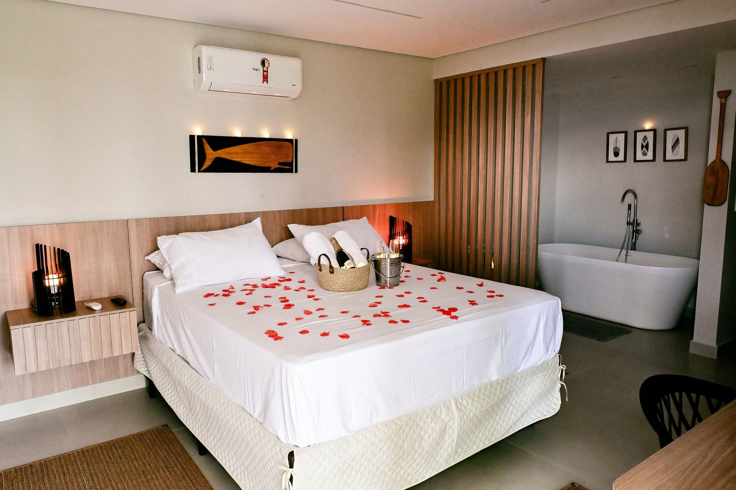 Habitación de hotel con cama, mesita de noche, lámpara y aire acondicionado instalado en la pared.