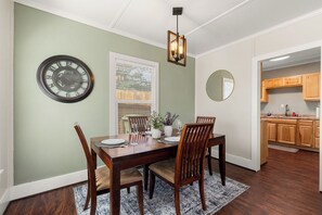 A dining room with a wooden table, chairs, a clock, and a mirror on the wall. - The Nook on 4th Street (Prescott)