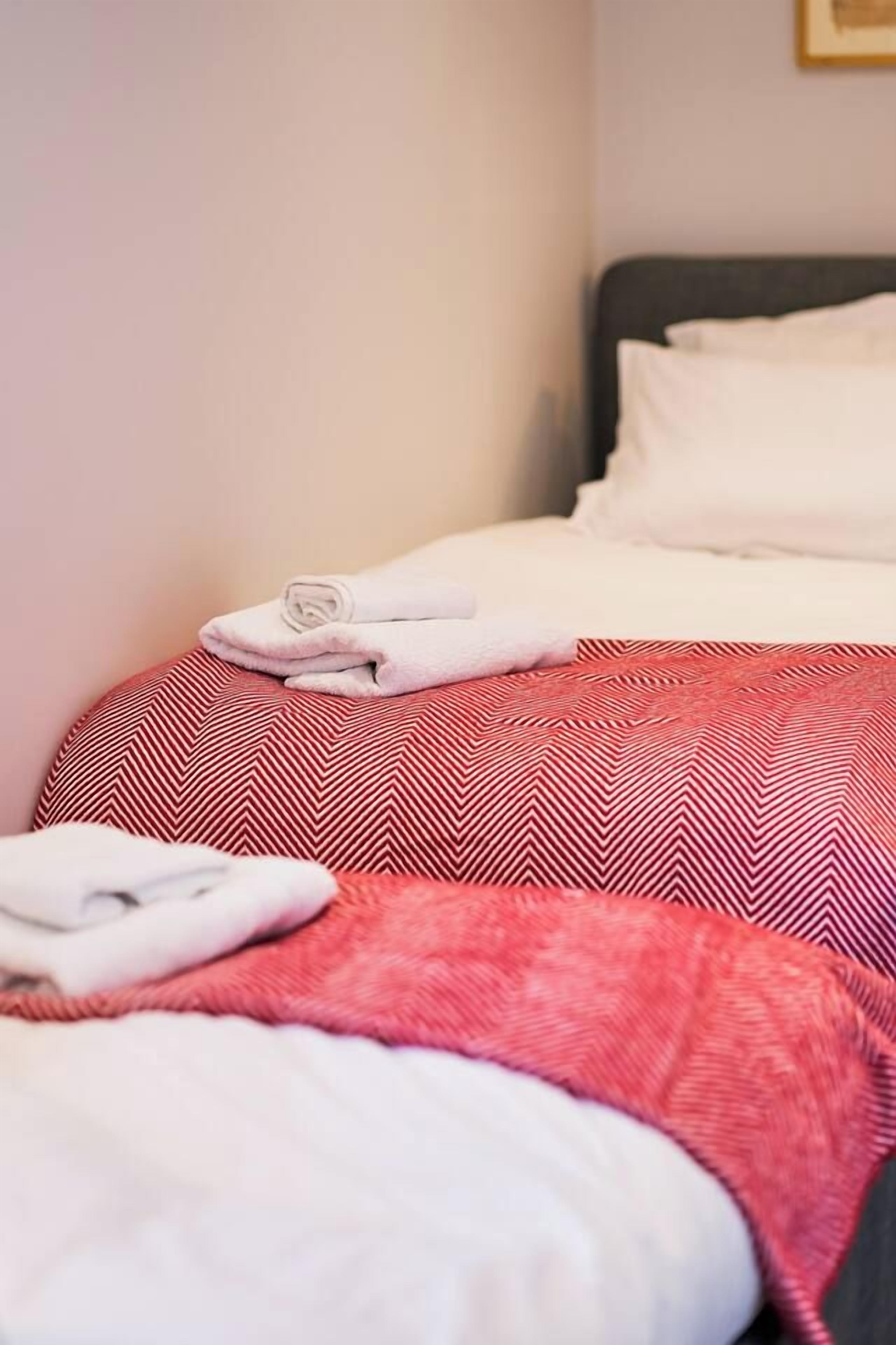 Habitación de hotel con dos camas, cada una con una colcha de diseño rojo y blanco.