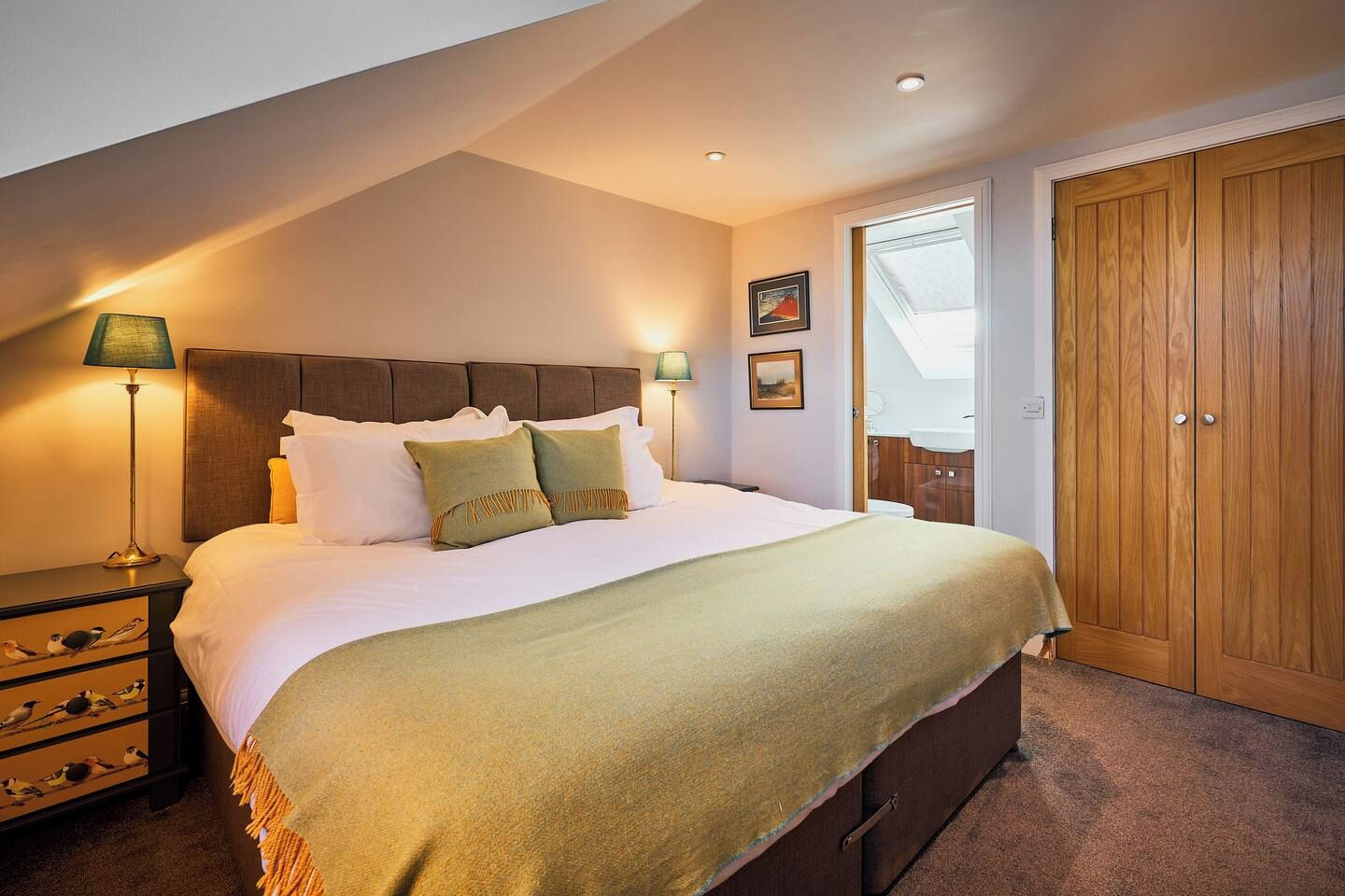 A bedroom with a large bed, two bedside tables, a wardrobe, and a skylight.