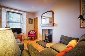 Un salon chaleureux avec une cheminée, un téléviseur et des fauteuils confortables.
