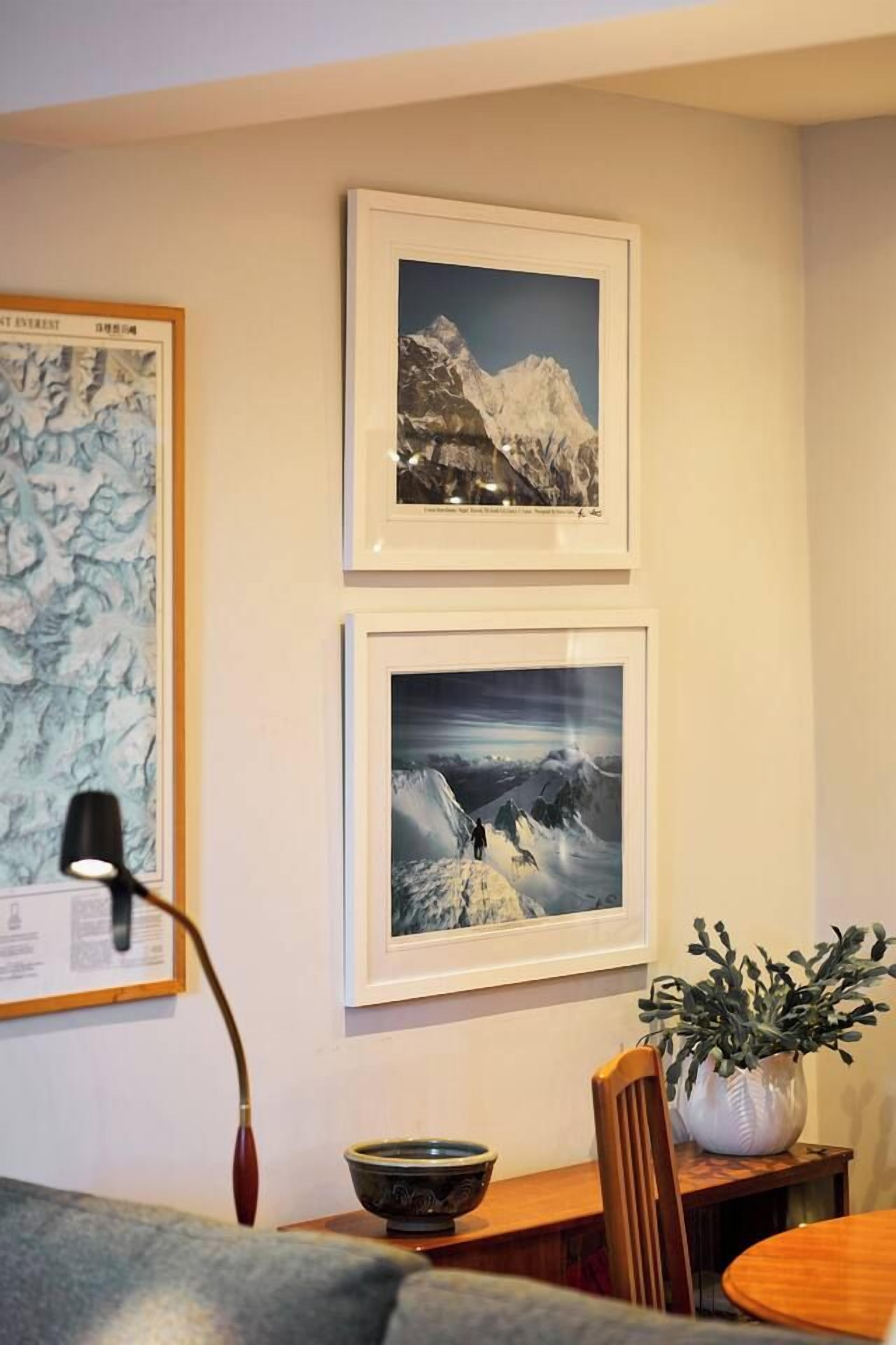 Una habitación con una mesa de comedor, sillas, una lámpara y cuadros en la pared.