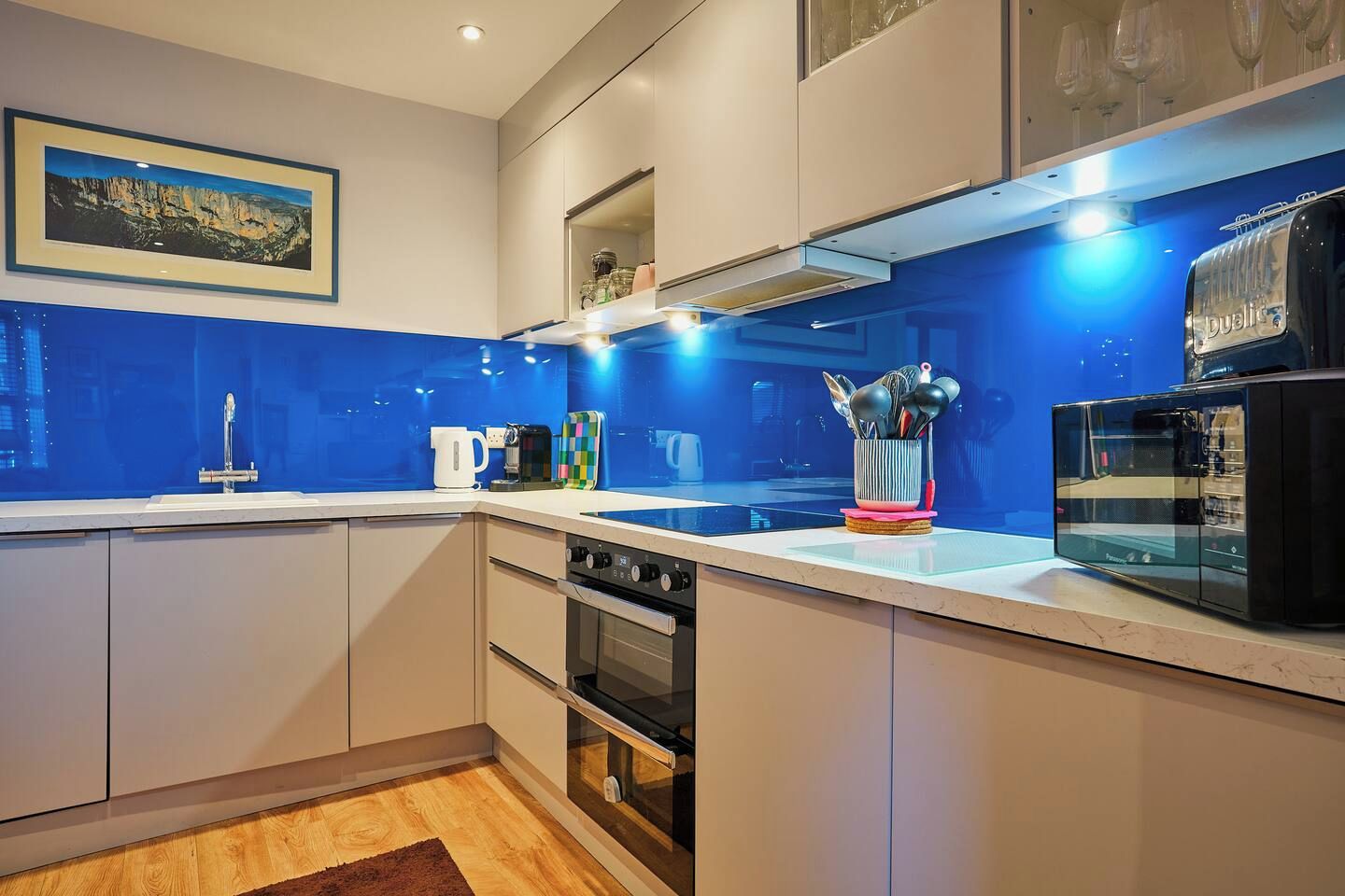 Une cuisine moderne avec un revêtement mural bleu, des appareils en acier inoxydable et une machine à café.