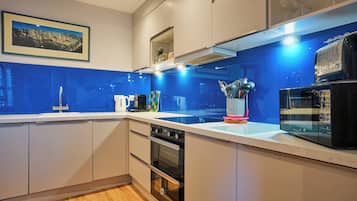 Une cuisine moderne avec un revêtement mural bleu, des appareils en acier inoxydable et une machine à café.