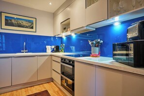 Une cuisine moderne avec un revêtement mural bleu, des appareils en acier inoxydable et une machine à café.