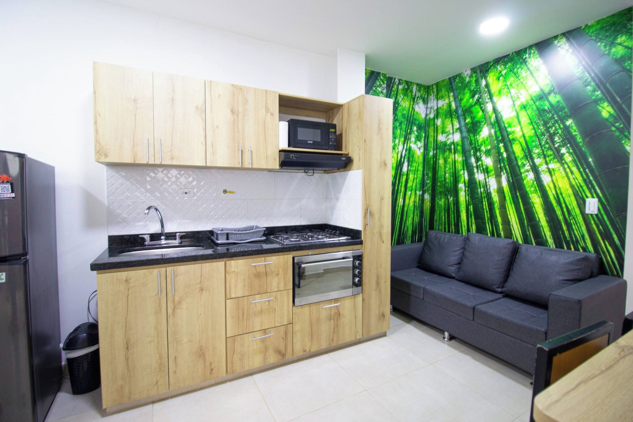 Una cocina compacta con armarios de madera, horno empotrado y microondas.