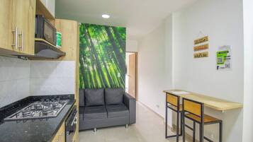 A compact kitchen with a gas stove, a sofa, and a small table.