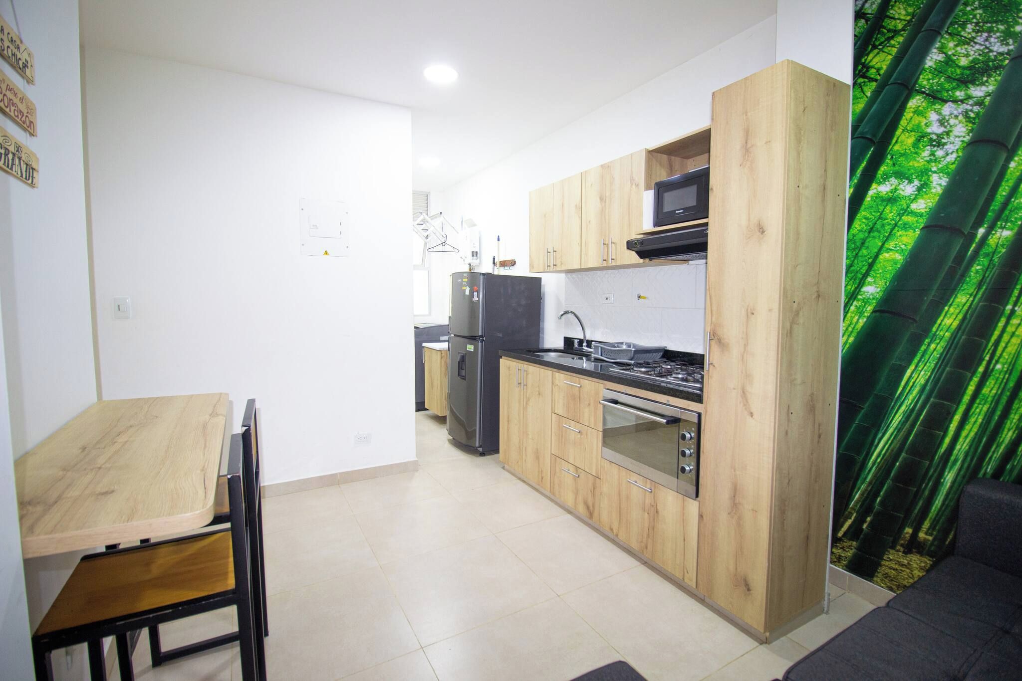 Una cocina compacta con armarios de madera, horno empotrado y microondas.