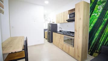 Una cocina compacta con armarios de madera, horno empotrado y microondas.