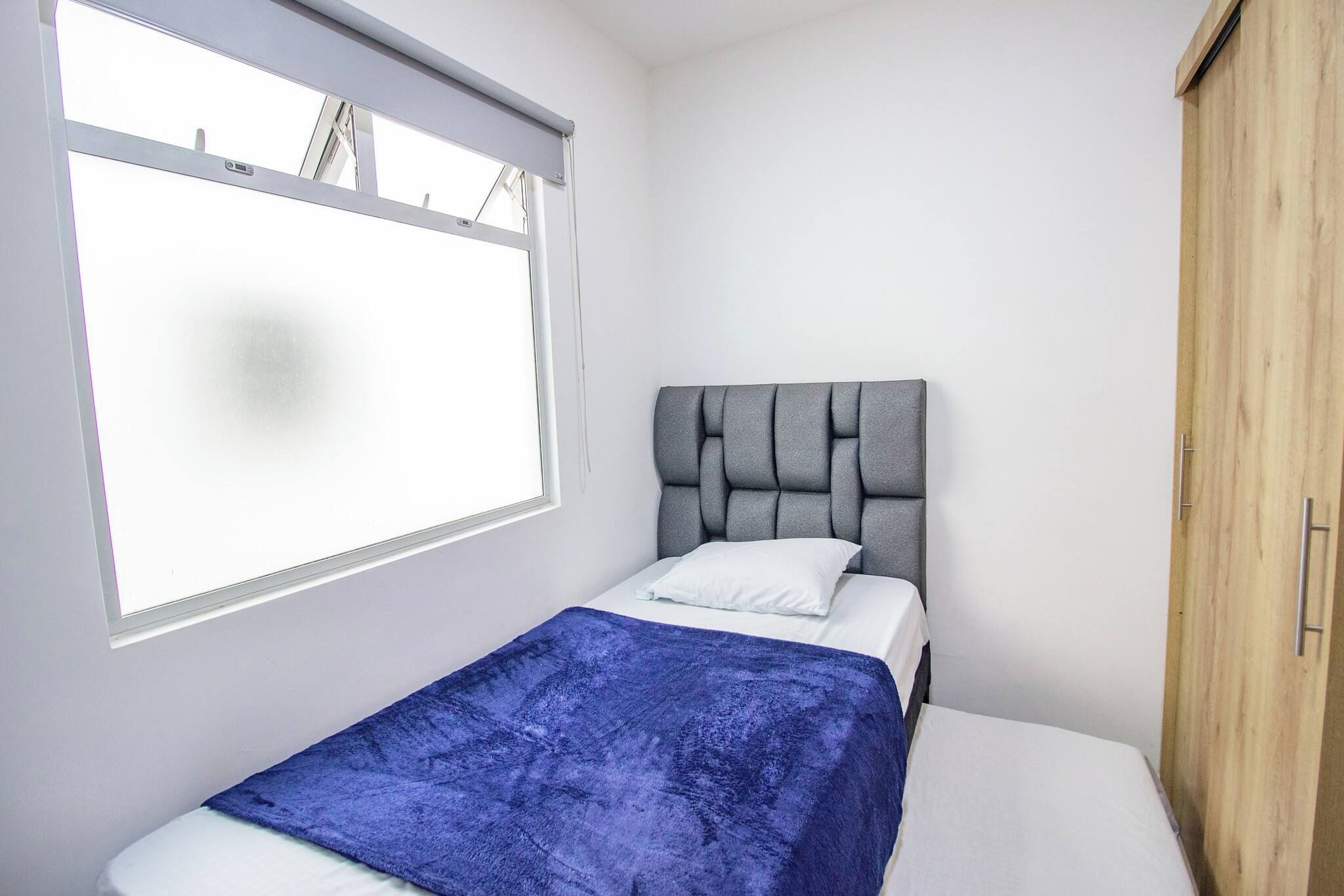 A bedroom with a bed, a window, and a wardrobe.